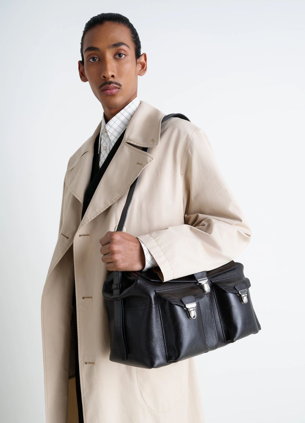 Lemaire Week-End Gear Bag in Glossy Vegetable-Tanned Leather, model shot, three-quarter view handheld with closure straps