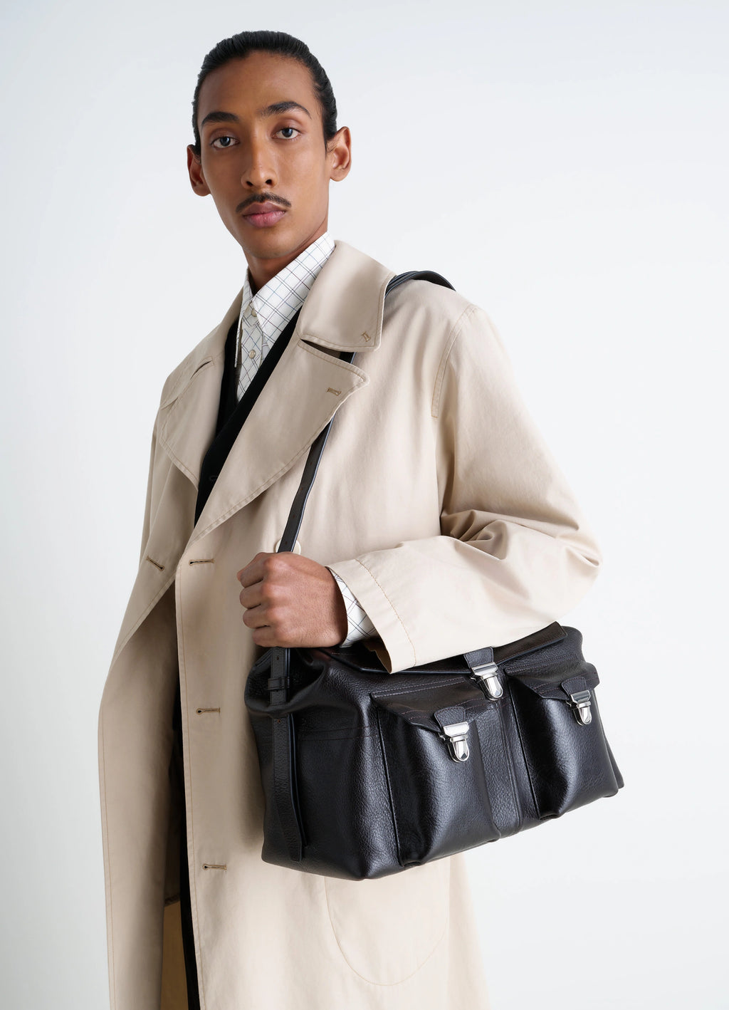 Lemaire Week-End Gear Bag in Glossy Vegetable-Tanned Leather, model shot, three-quarter view handheld with closure straps