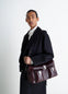 Lemaire Week-End Gear Bag in Glossy Vegetable-Tanned Leather, model shot, Side view Adjustable shoulder strap