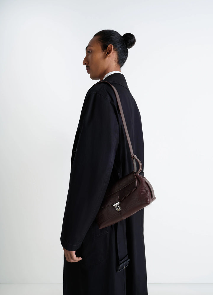 Lemaire Small Gear Bag in Glossy Vegetable-Tanned Leather, model shot, side view flap closure with clip clasp