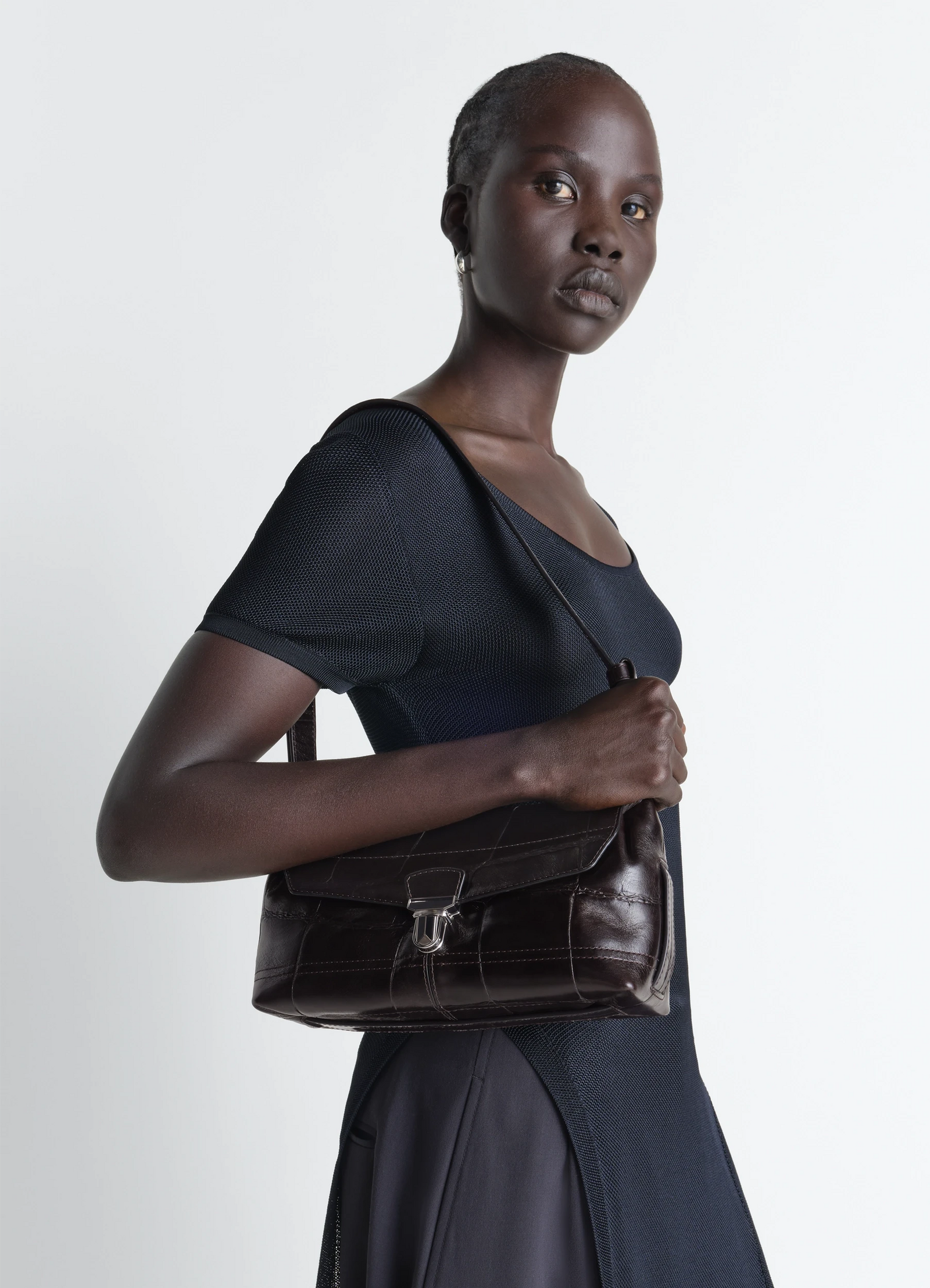 Small soft gear bag in black croco-embossed leather, model shot, side view shoulder strap detail