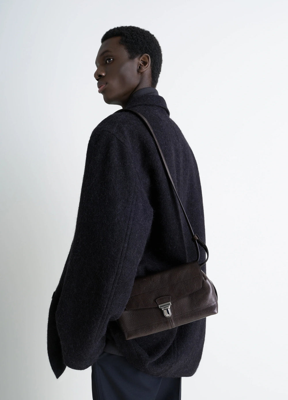 Lemaire Small Gear Bag in Glossy Vegetable-Tanned Leather, model shot, Side view Adjustable shoulder strap