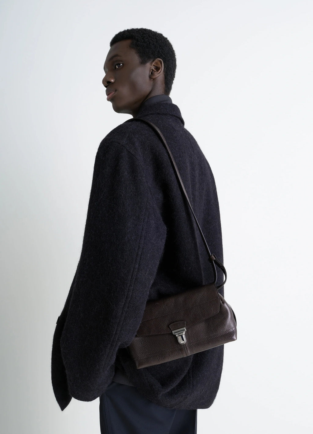 Lemaire Small Gear Bag in Glossy Vegetable-Tanned Leather, model shot, Side view Adjustable shoulder strap