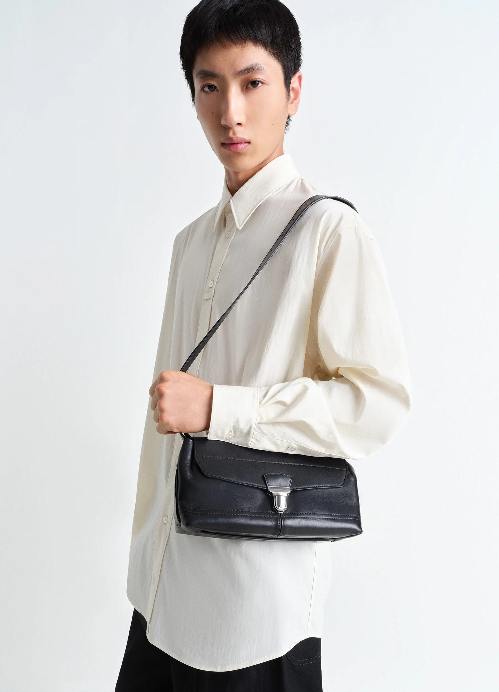 Lemaire small gear bag in black vegetable-tanned nappa leathe, model shot, crossbody view sleek buckle detail