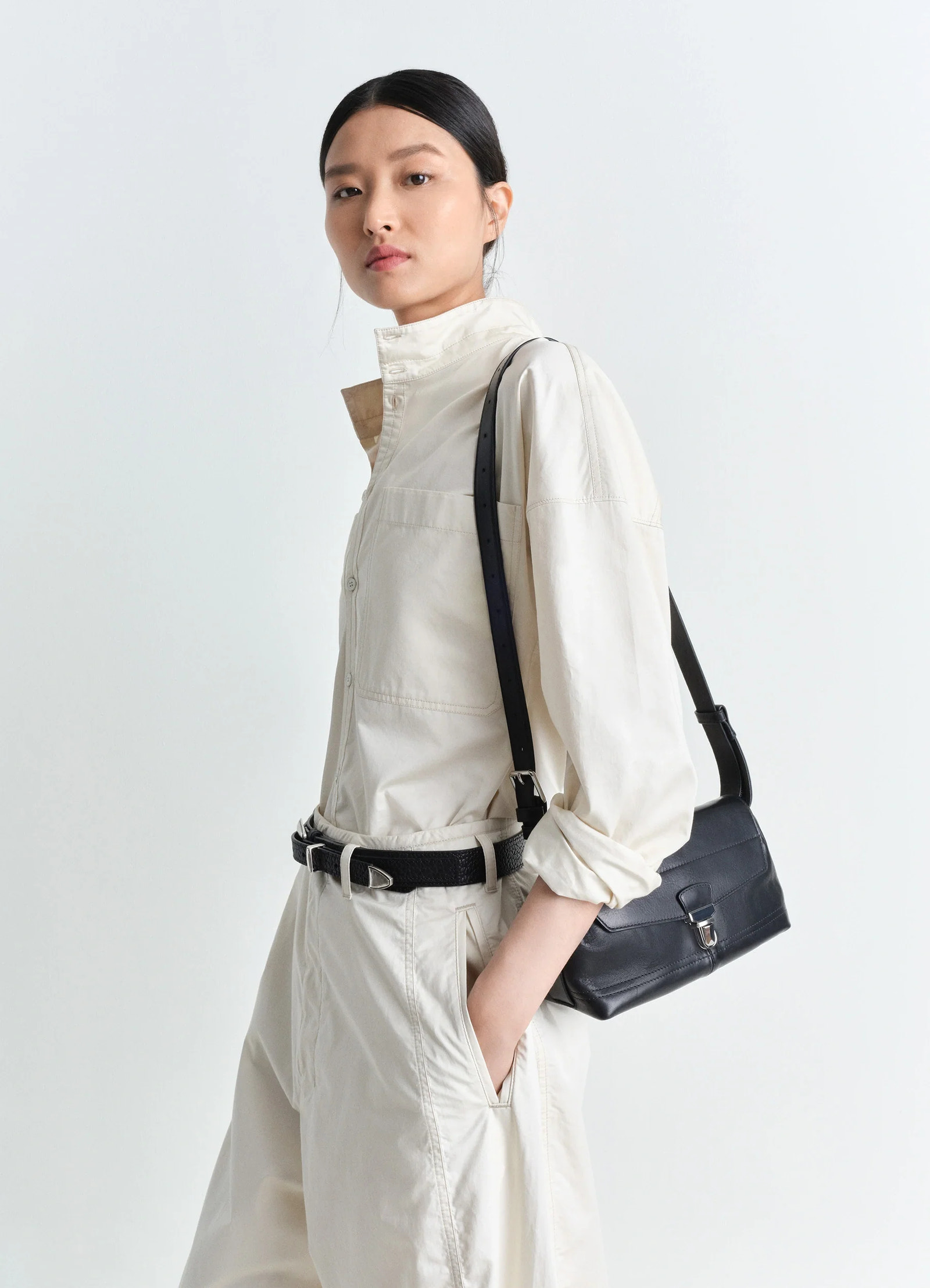 Lemaire small gear bag in black vegetable-tanned nappa leathe, model shot, side view draped shoulder carry