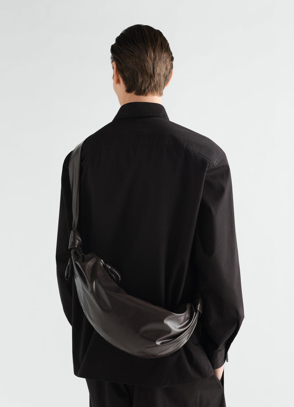 Medium soft croissant bag in dark brown paper leather LEMAIRE worn by model back view