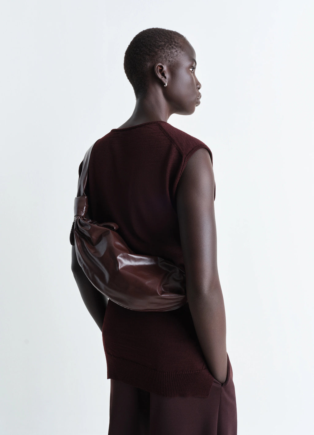 Lemaire Small Soft Croissant in Paper-effect leather, model shot, three-quarter view draped over shoulder