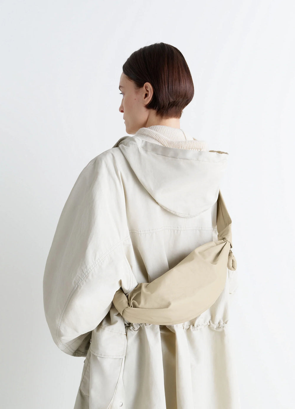 Lemaire Small Soft Croissant in Beige Paper-Effect Leather, model shot, over shoulder view knotted strap detail