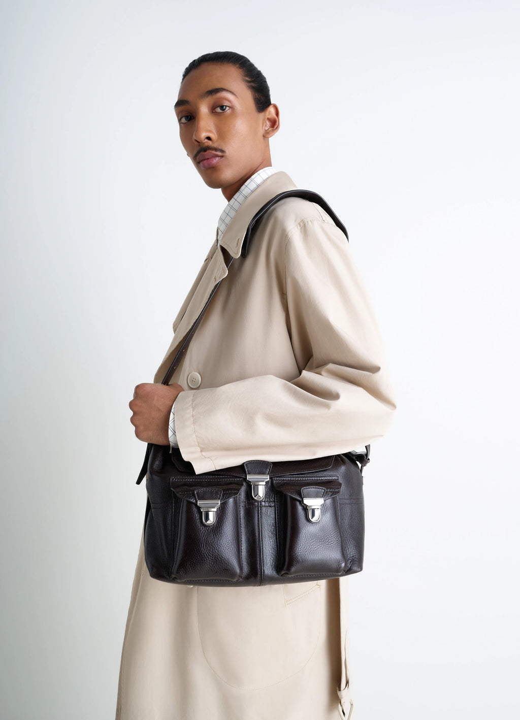 Lemaire Medium Gear Bag in Glossy Vegetable-Tanned Leather, model shot, over-the-shoulder view worn crossbody with clasp deta