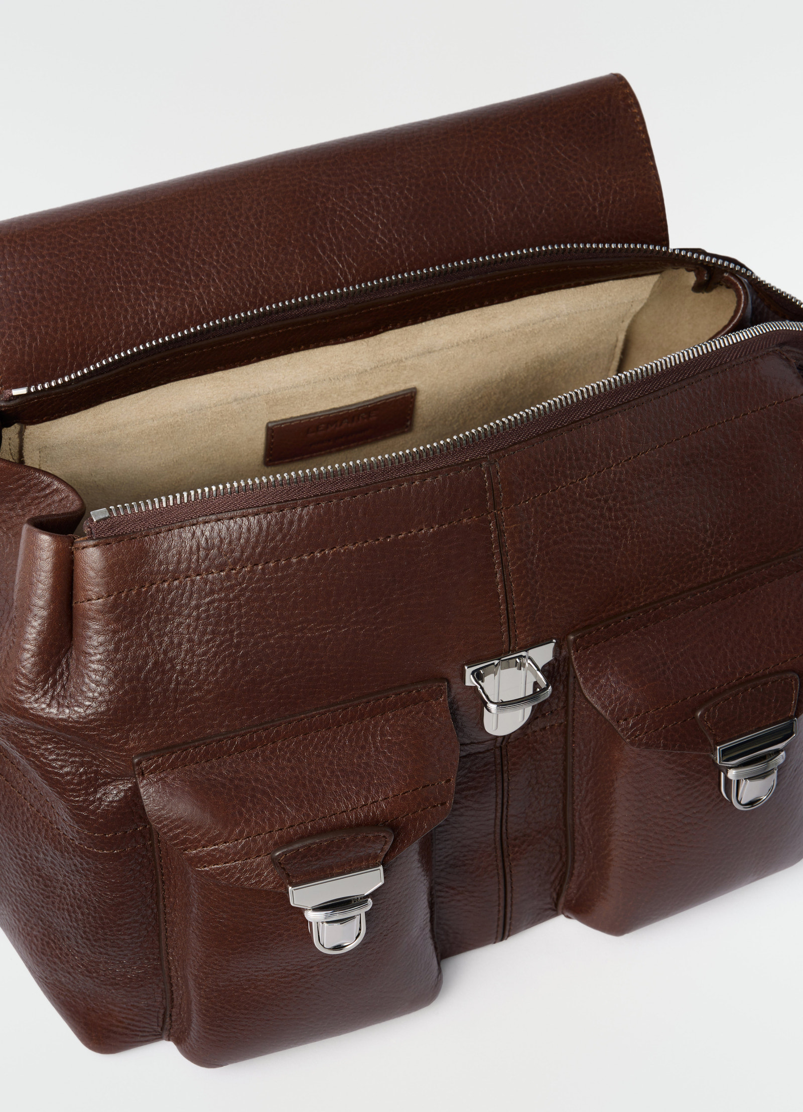 Medium brown leather gear bag by lemaire with silver clasps and beige interior close-up detail