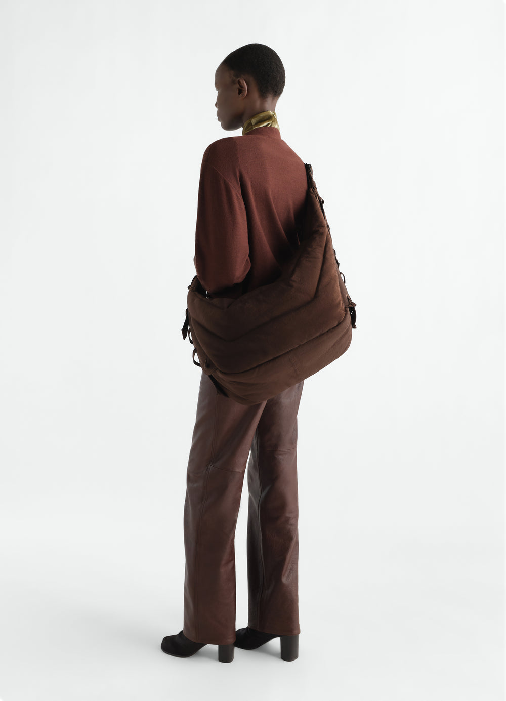 Large soft brown nylon canvas game bag LEMAIRE worn by model back view with brown leather pants