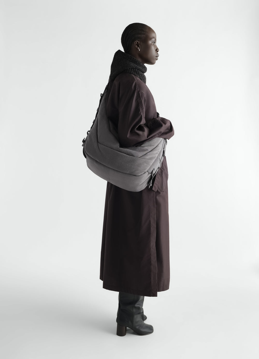 Large soft grey nylon canvas Game Bag LEMAIRE worn by model side view with purple coat and black boots