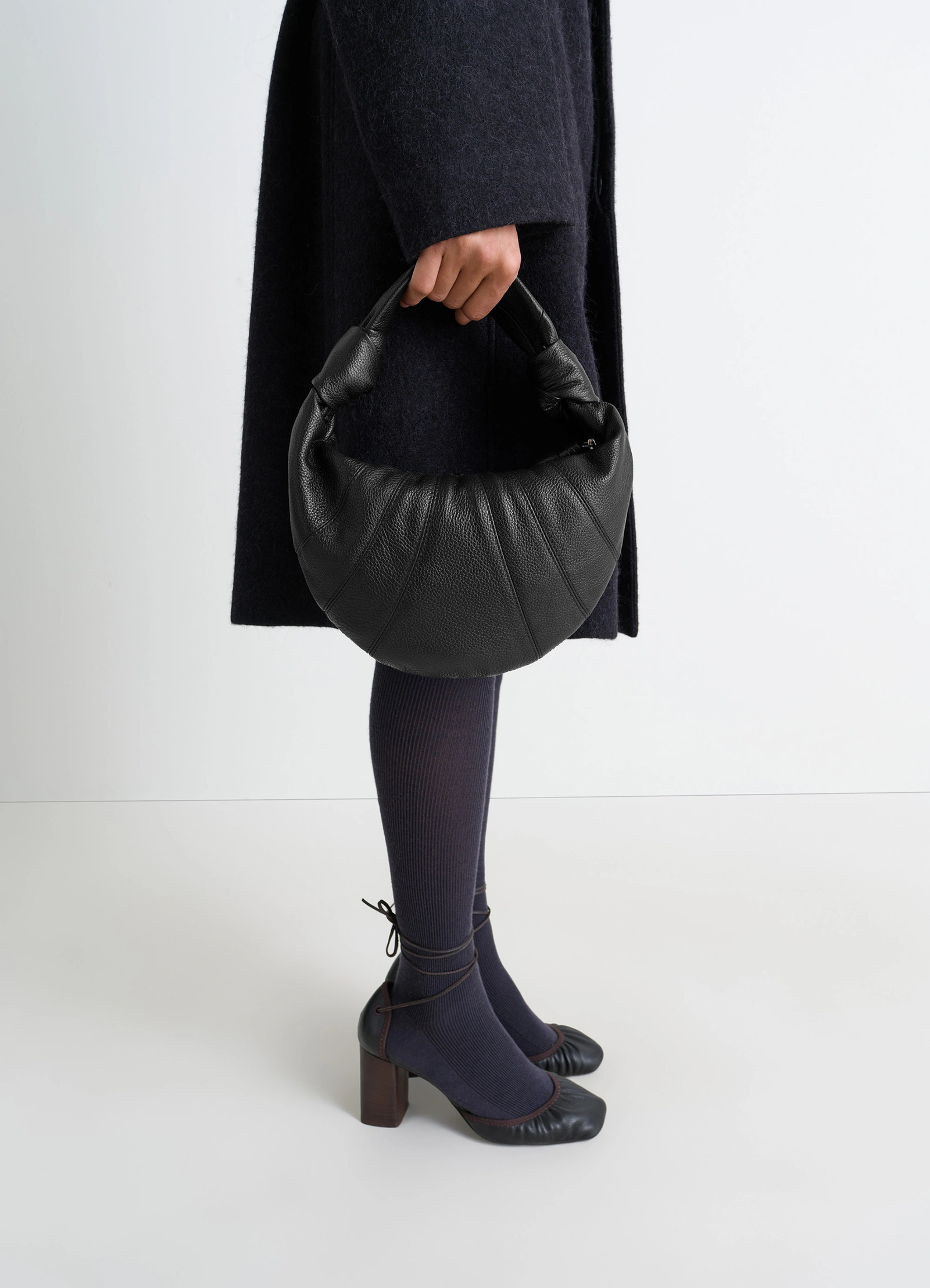 Mini fortune croissant bag in black grained leather, model shot, side view knotted handle, half-moon shape