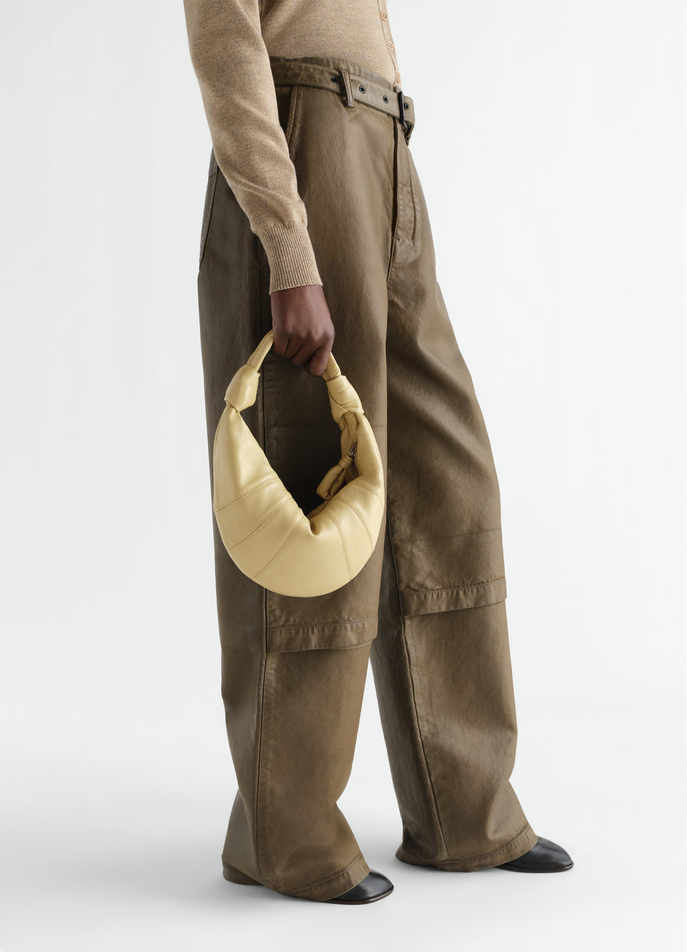 Mini Fortune Croissant leather bag beige LEMAIRE held by model wearing brown pants front view