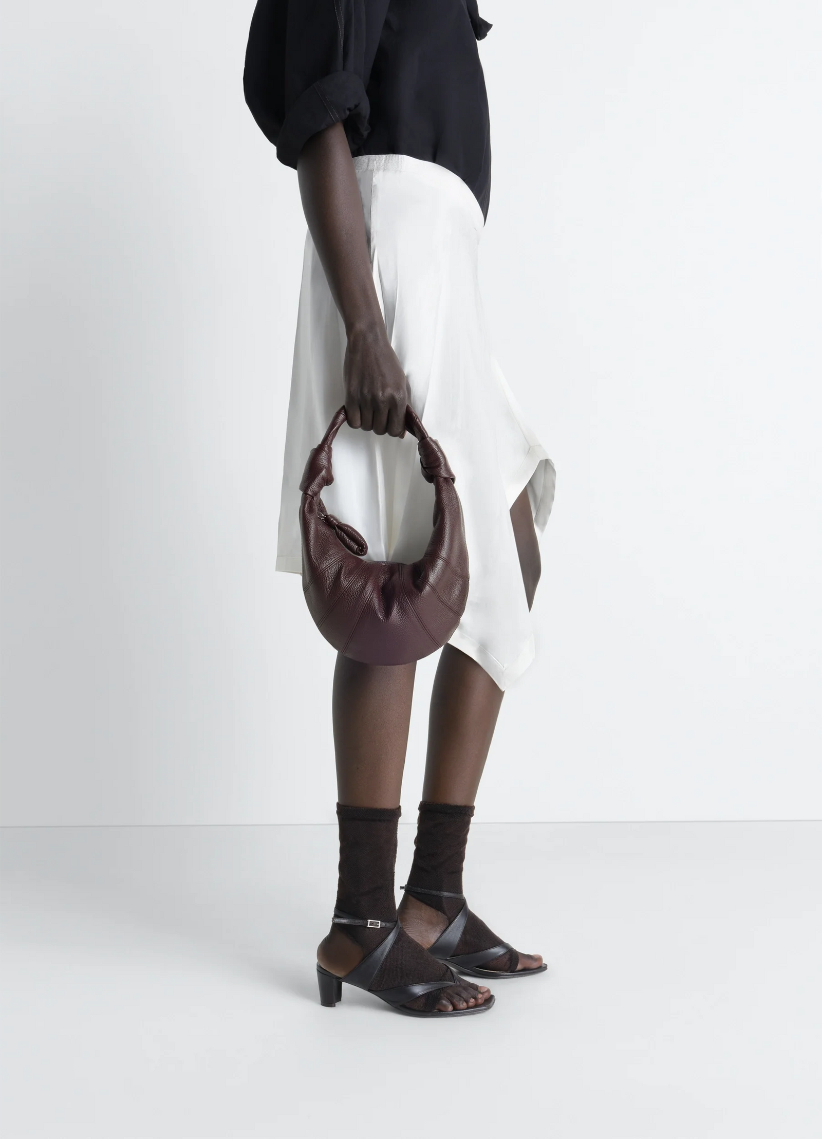 Mini fortune croissant bag in grained leather, model shot, handheld side view crescent shape design