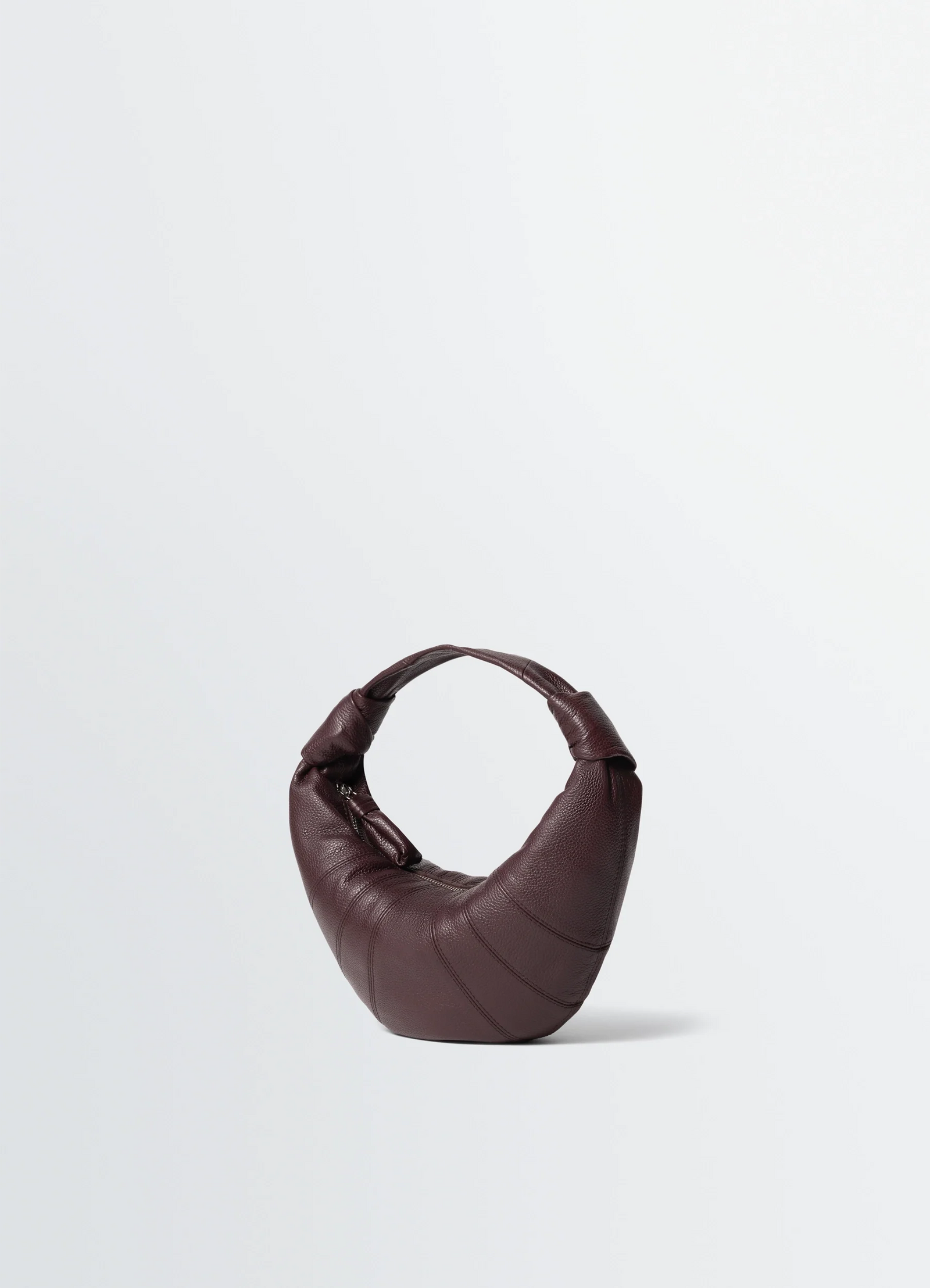 Mini fortune croissant bag in grained leather, product shot, angled bottom view arched handle detail