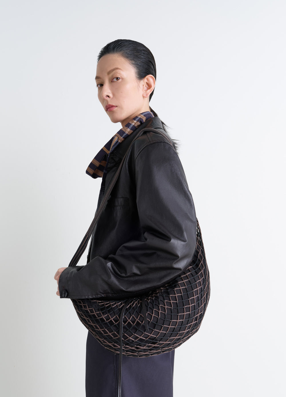 Lemaire Croissant Filt Bag in Black Nylon Net, model shot, side view carried underarm