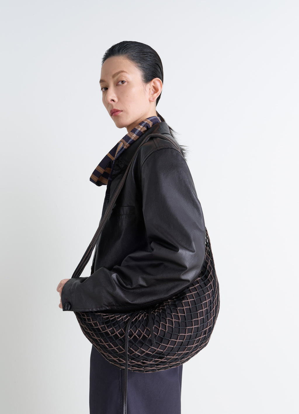 Lemaire Croissant Filt Bag in Black Nylon Net, model shot, side view carried underarm