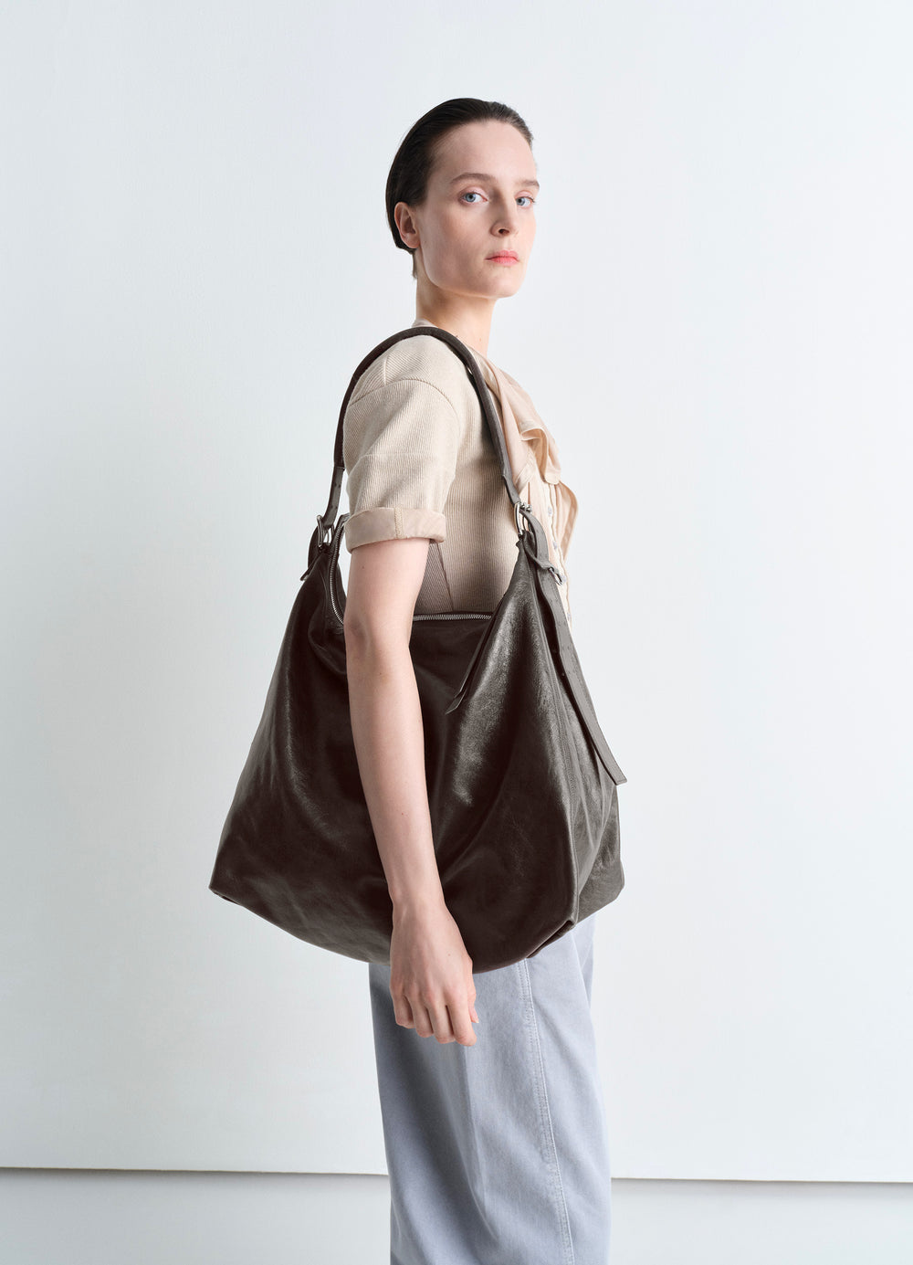 Lemaire Belted Hobo Bag in Thin Shiny Leather, model shot, Side view Adjustable strap detail