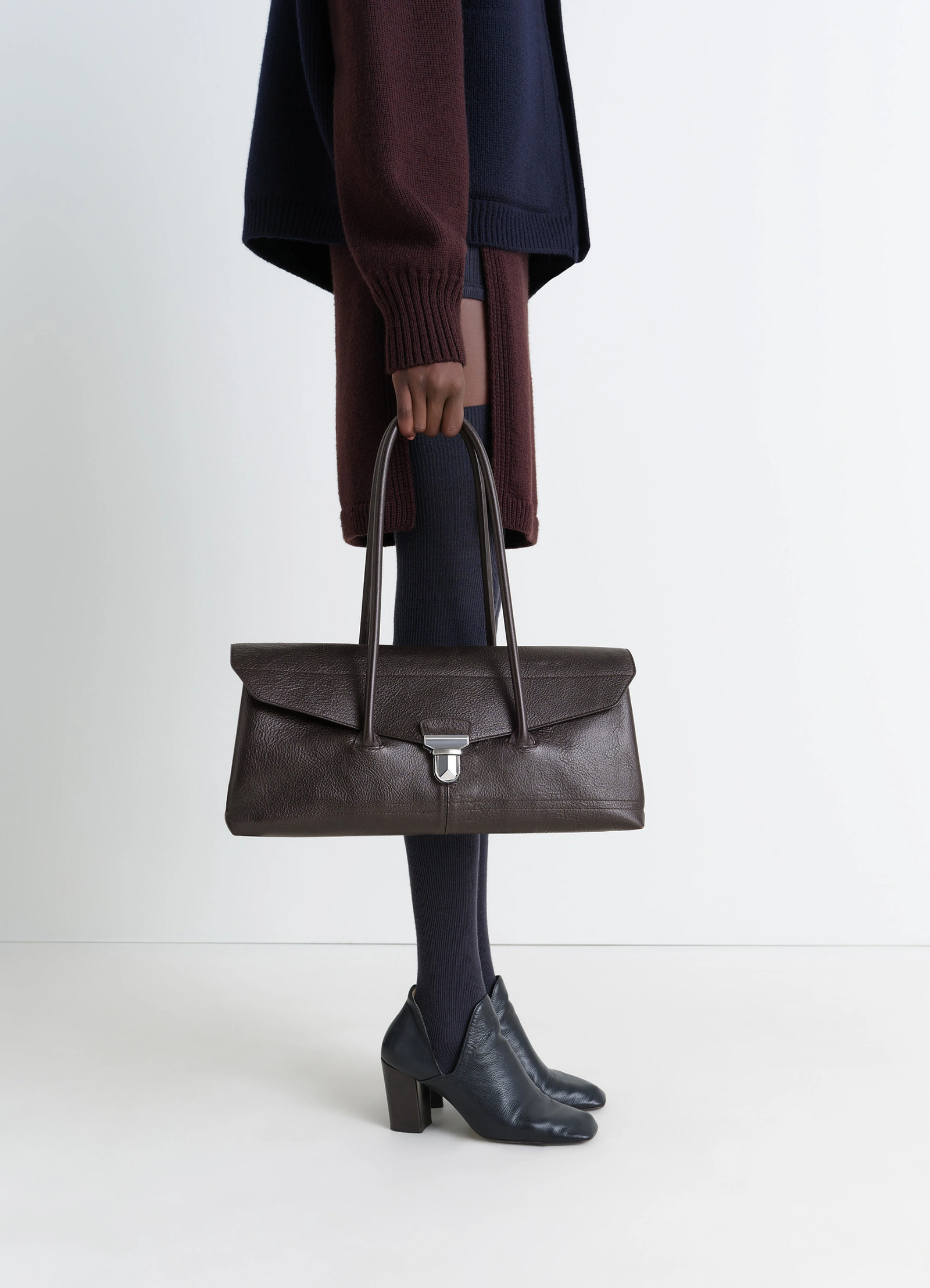 Lemaire shoulder gear bag in dark brown vegetable-tanned leather, model shot, side view flap closure with metal clip