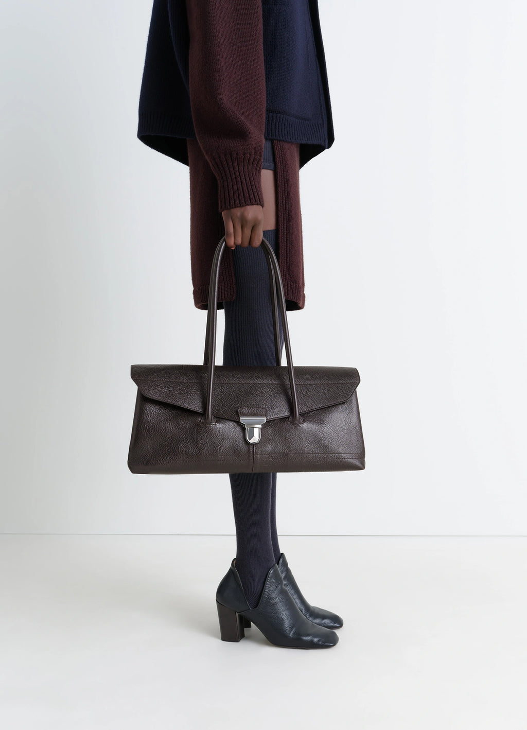 Lemaire Shoulder Gear Bag in Dark Brown Vegetable-Tanned Leather, model shot, Side view Flap closure with metal clip