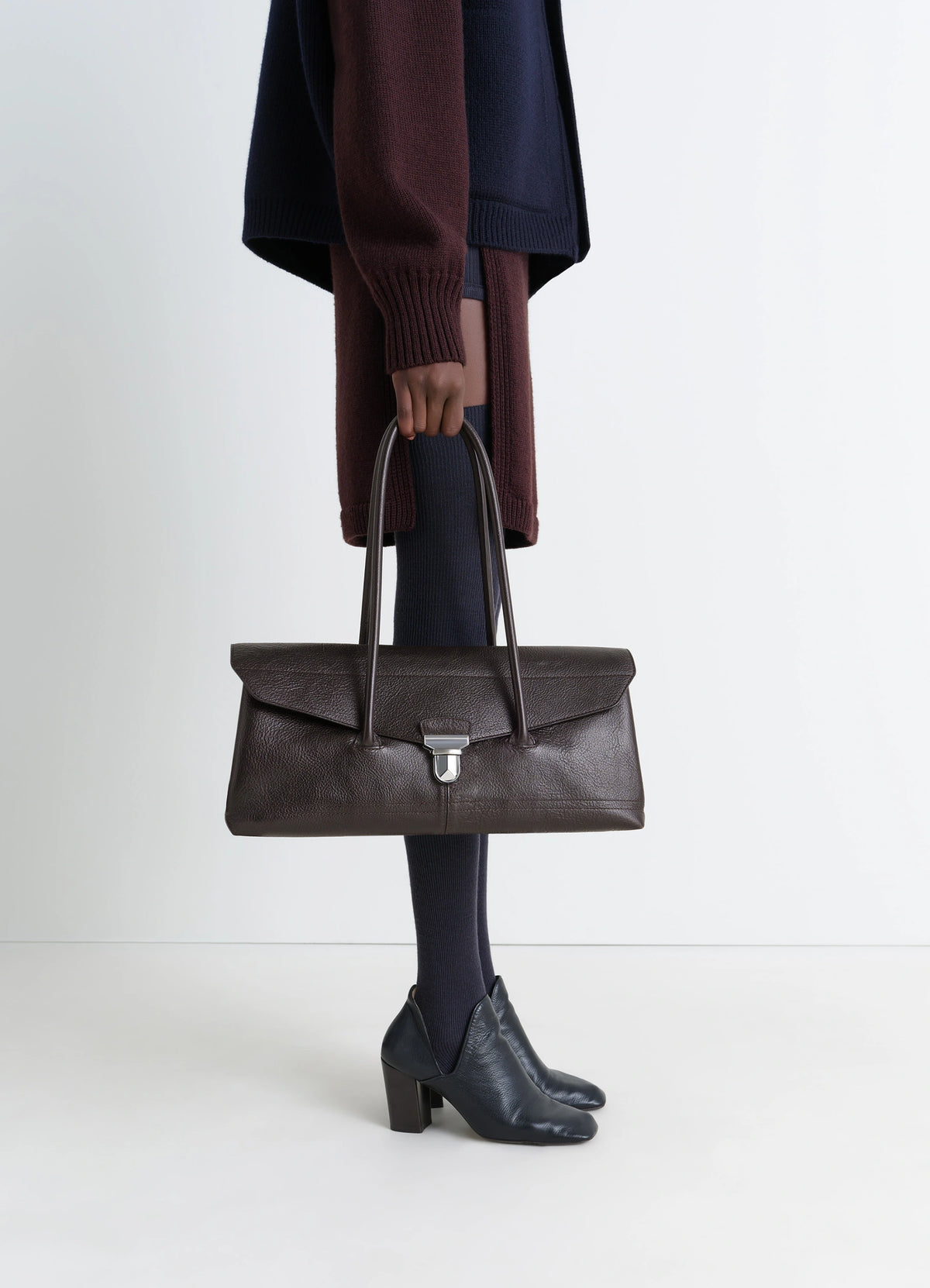 Lemaire Shoulder Gear Bag in Dark Brown Vegetable-Tanned Leather, model shot, Side view Flap closure with metal clip