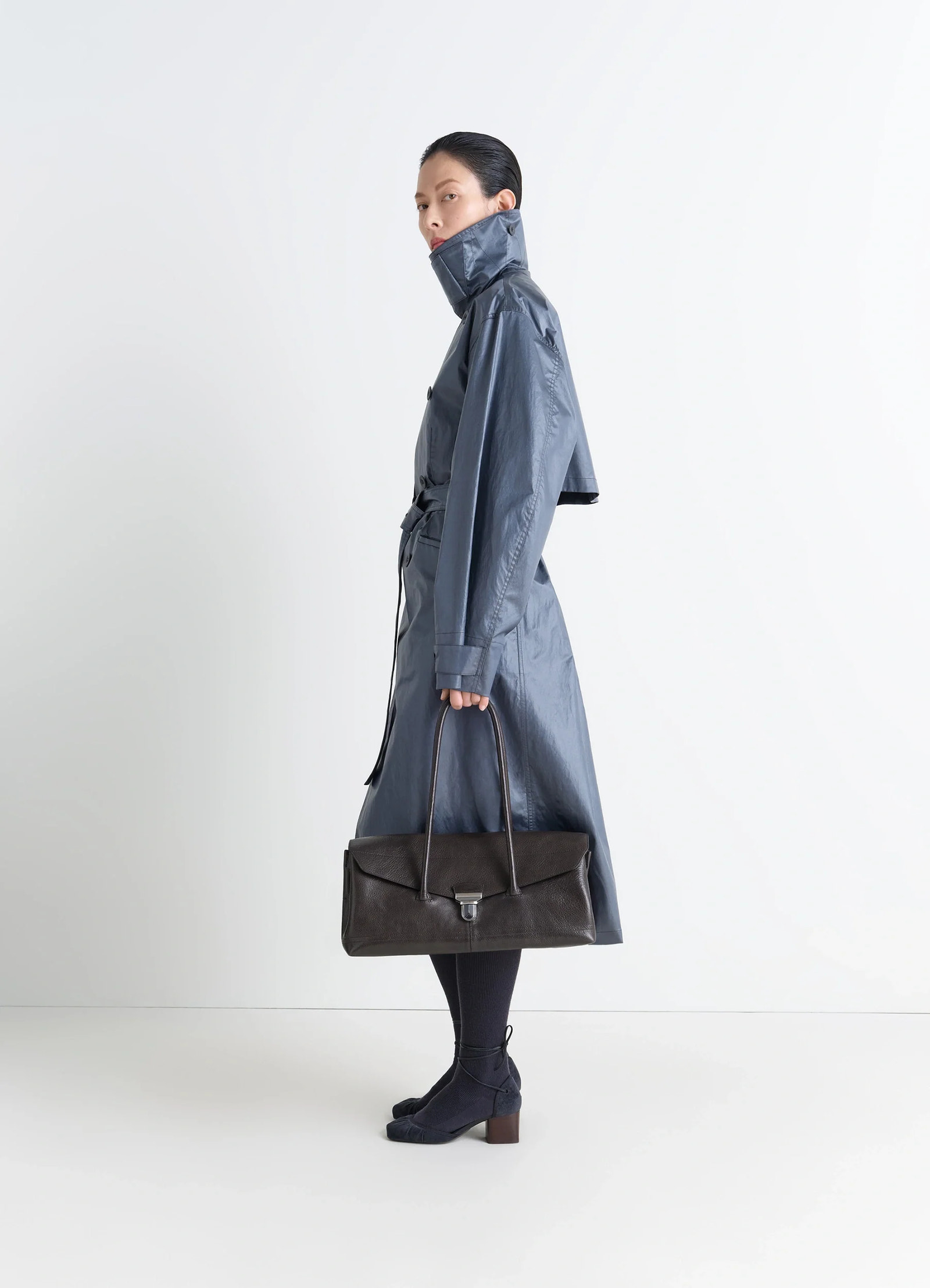 Lemaire shoulder gear bag in glossy vegetable-tanned leather, model shot, side view features flap closure