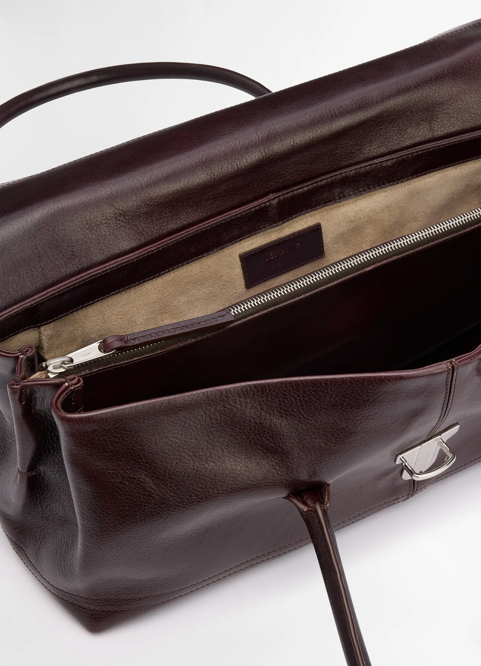 Lemaire shoulder gear bag in glossy vegetable-tanned leather, product shot, top detail view zippered compartment interior