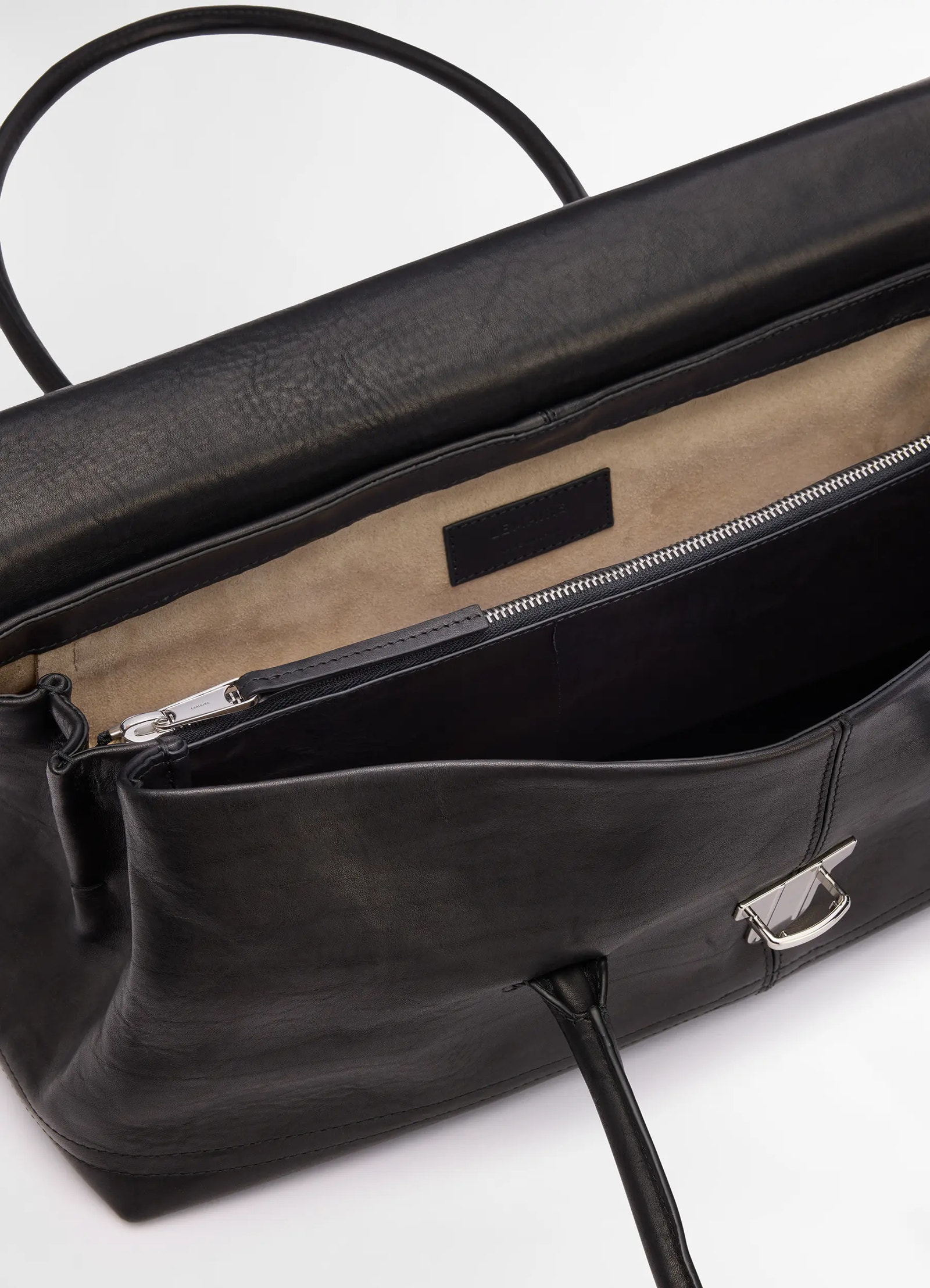 Lemaire shoulder gear bag in black vegetable tanned nappa, product shot, interior top view metallic clasp detail