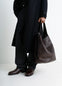 Belted Tote Bag in LWG Gold-certified grained leather, model shot, side view worn by model with dark coat