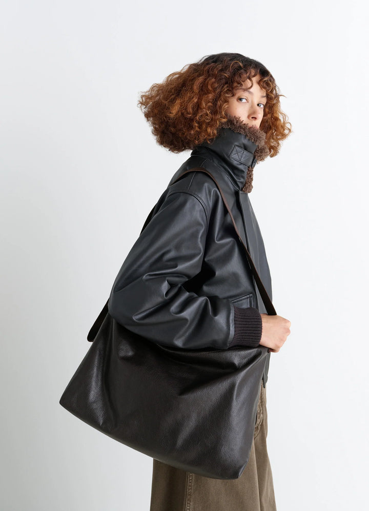 LARGE FOLIO BAG in vegetable-tanned grained leather, model shot, side view adjustable nylon strap