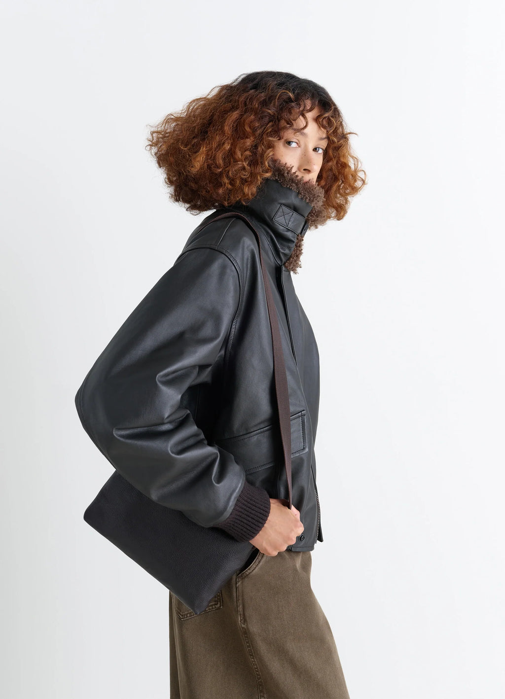 Small Folio Bag in Vegetable-tanned goat-effect leathe, model shot, Side view Worn on shoulder with strap