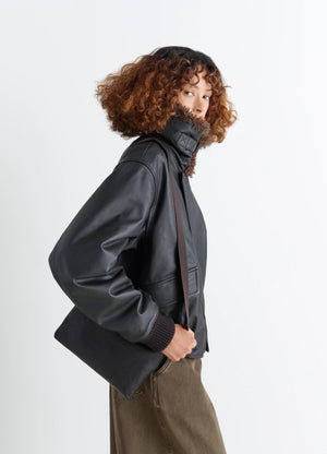 Small Folio Bag in Vegetable-tanned goat-effect leathe, model shot, Side view Worn on shoulder with strap