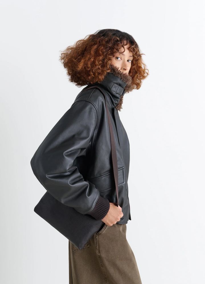 Small Folio Bag in Vegetable-tanned goat-effect leathe, model shot, Side view Worn on shoulder with strap