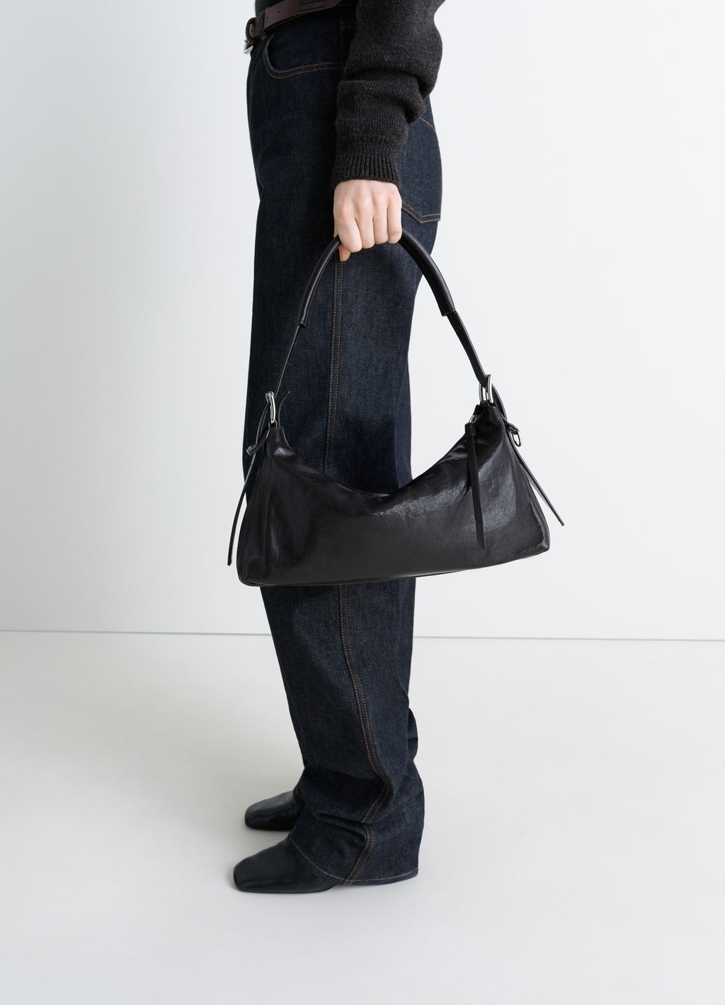 Belted Baguette Bag in Shiny Paper Lux Leather, model shot, handheld porte view sleek elongated shape