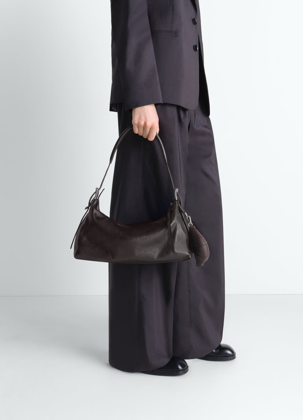 Sac belted baguette en cuir, coloris marron foncé, porté par un mannequin, vue de profil, ceinture visible