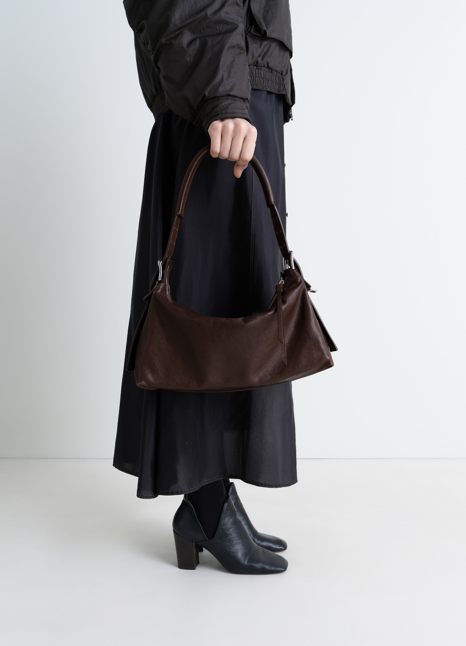 Belted baguette bag in brown paper lux leather, model shot, side view minimalist with leather strap