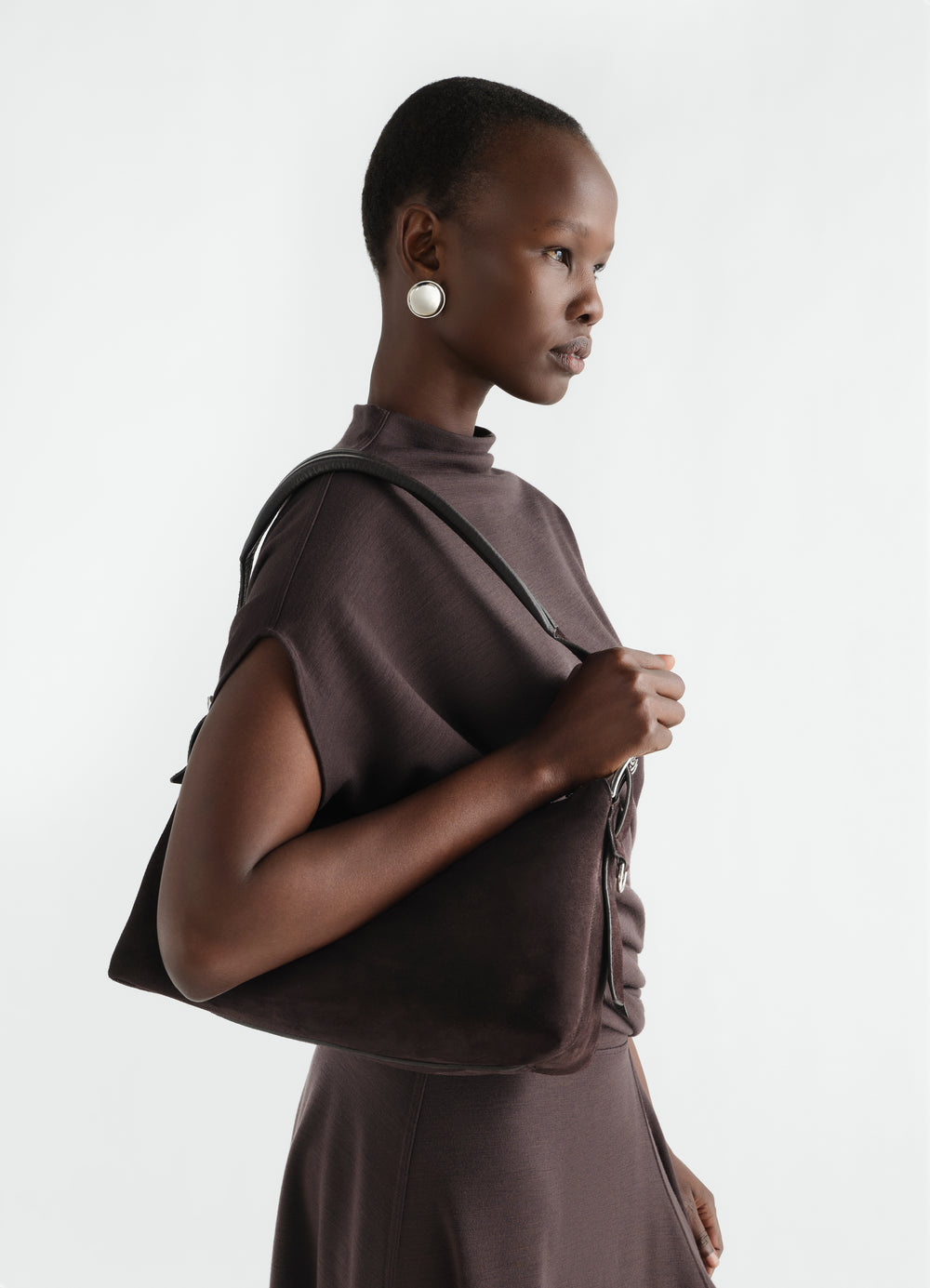 Belted baguette bag in dark brown suede leather worn by model side view LEMAIRE