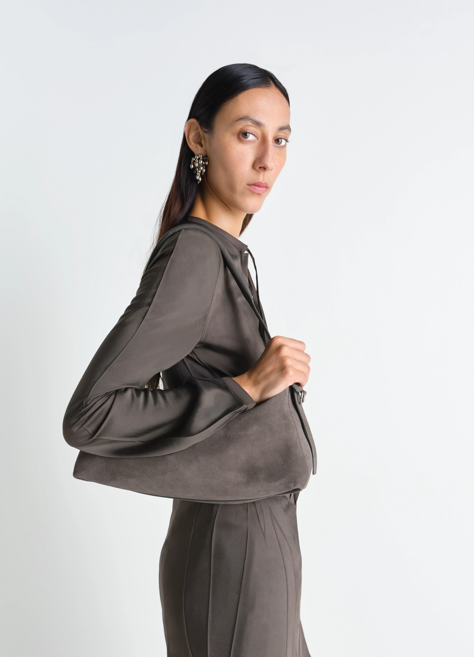 Belted baguette bag in dark taupe suede, model shot, side view fitted with wide sleeves