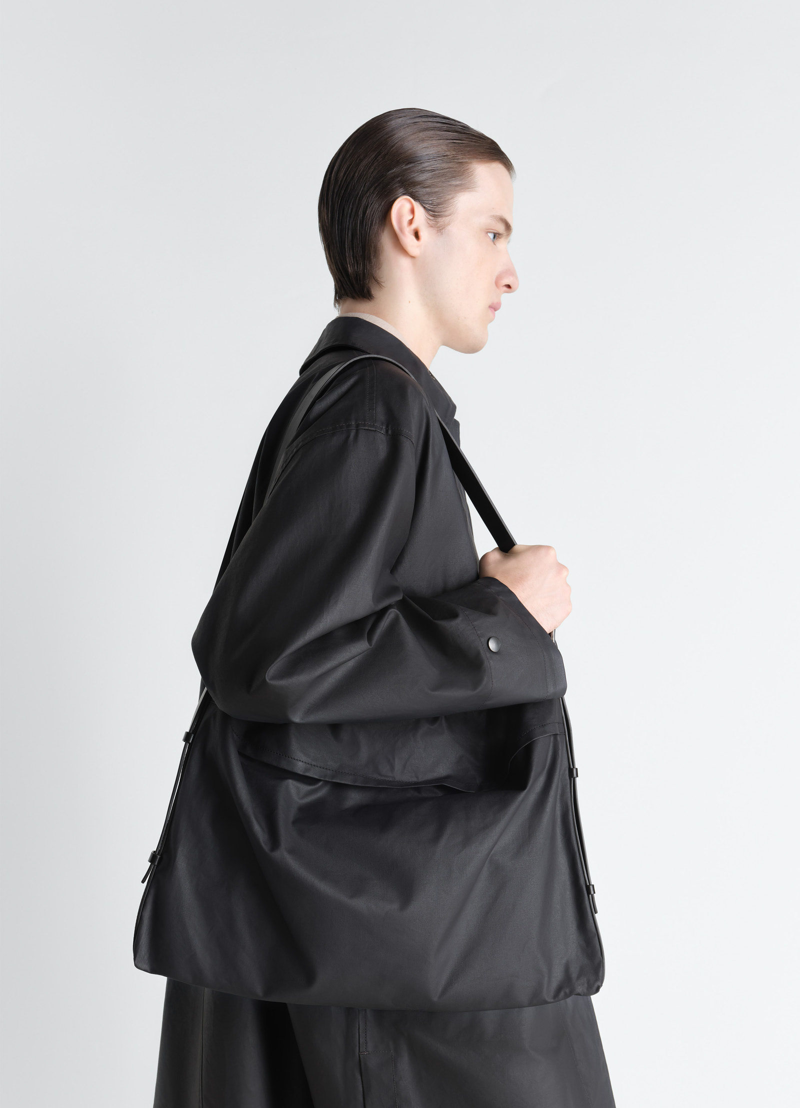 Medium trench pocket bag in water-repellant resinated cotton, model shot, over shoulder side view sleek minimalist design