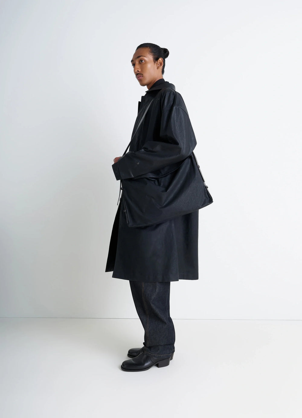 Trench Pocket Medium Bag in Black Resinated Cotton Canvas, model shot, three-quarter view oversized fit with shoulder strap