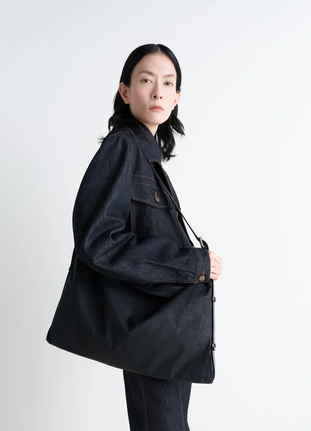 Trench Pocket Medium Bag in Black Resinated Cotton Canvas, model shot, Side view Utilitarian design