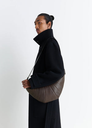 Rail Belt Medium Croissant Bag in Grained Leather in Brown, model shot, Side view Curved design with shoulder strap