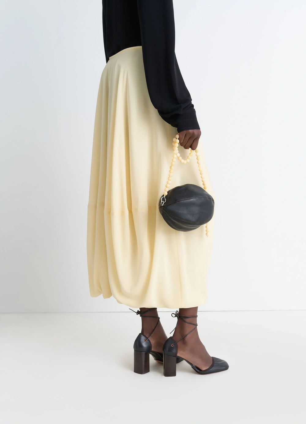 Lemaire Balloon Pouch in Black Nappa Lamb Leather, model shot, Side view Pearl pull tab