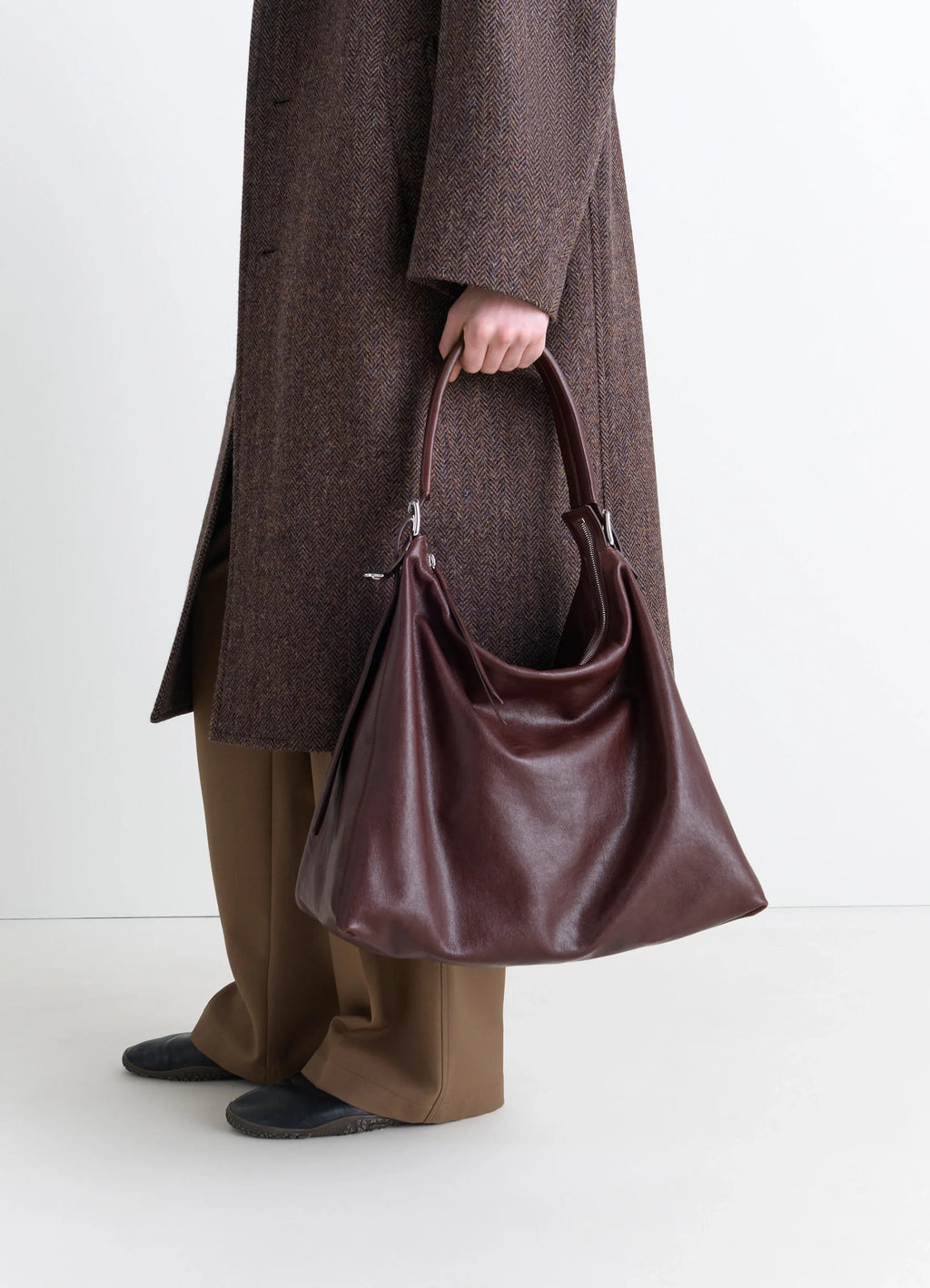 Belted Hobo Bag in Glazed Paper Leather, model shot, held by person slouchy silhouette