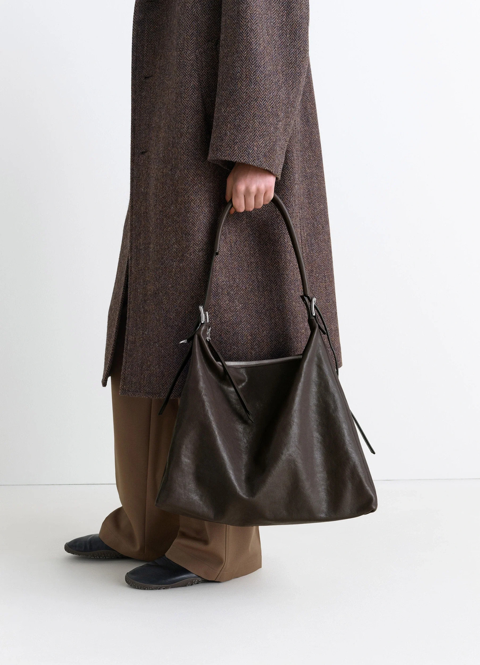 Belted hobo bag in glazed paper leather, model shot, porte side view minimalist utilitarian