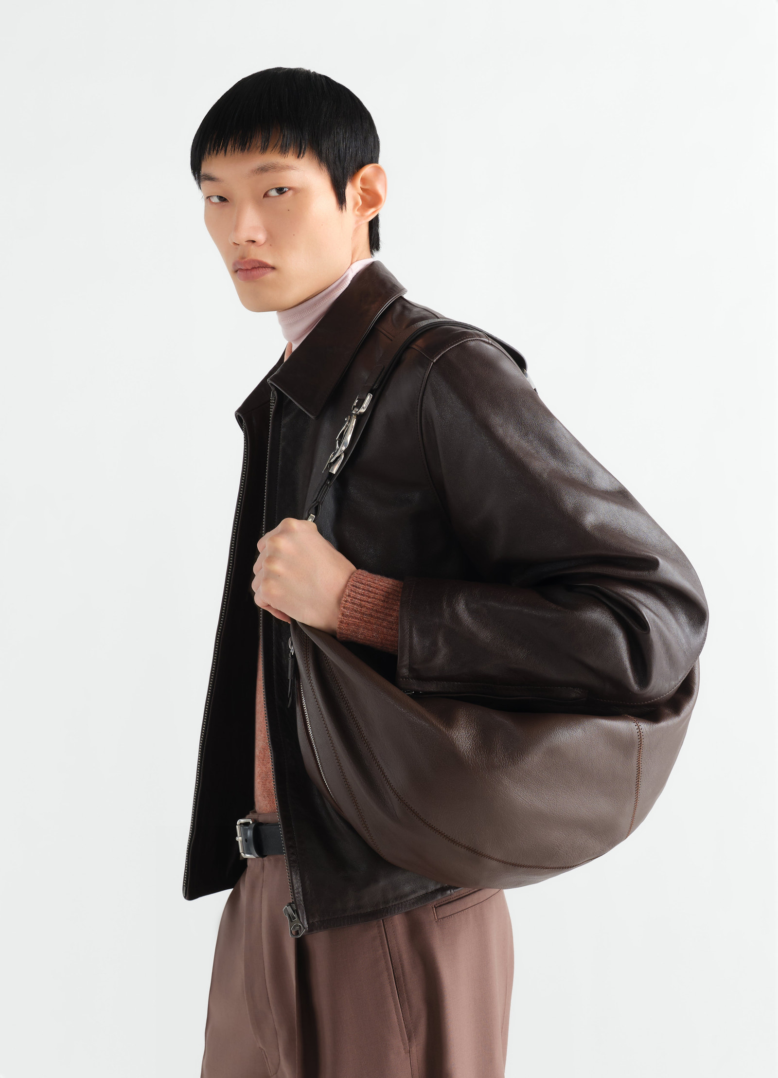 Large brown leather quiver clip bag lemaire worn by model side view with dark brown leather jacket and brown pants