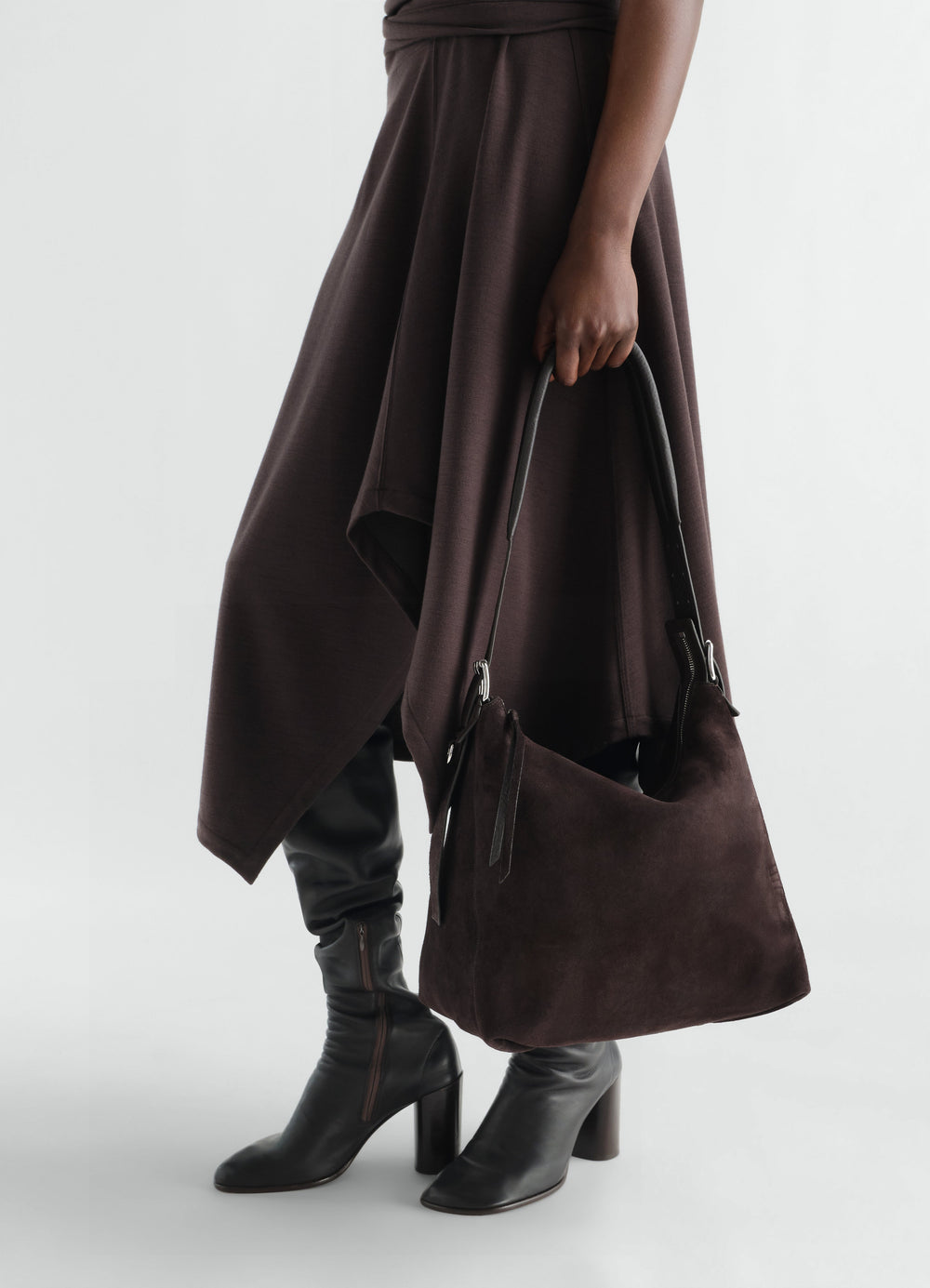 Small brown suede leather belted hobo bag LEMAIRE worn by model with skirt and black boots side view