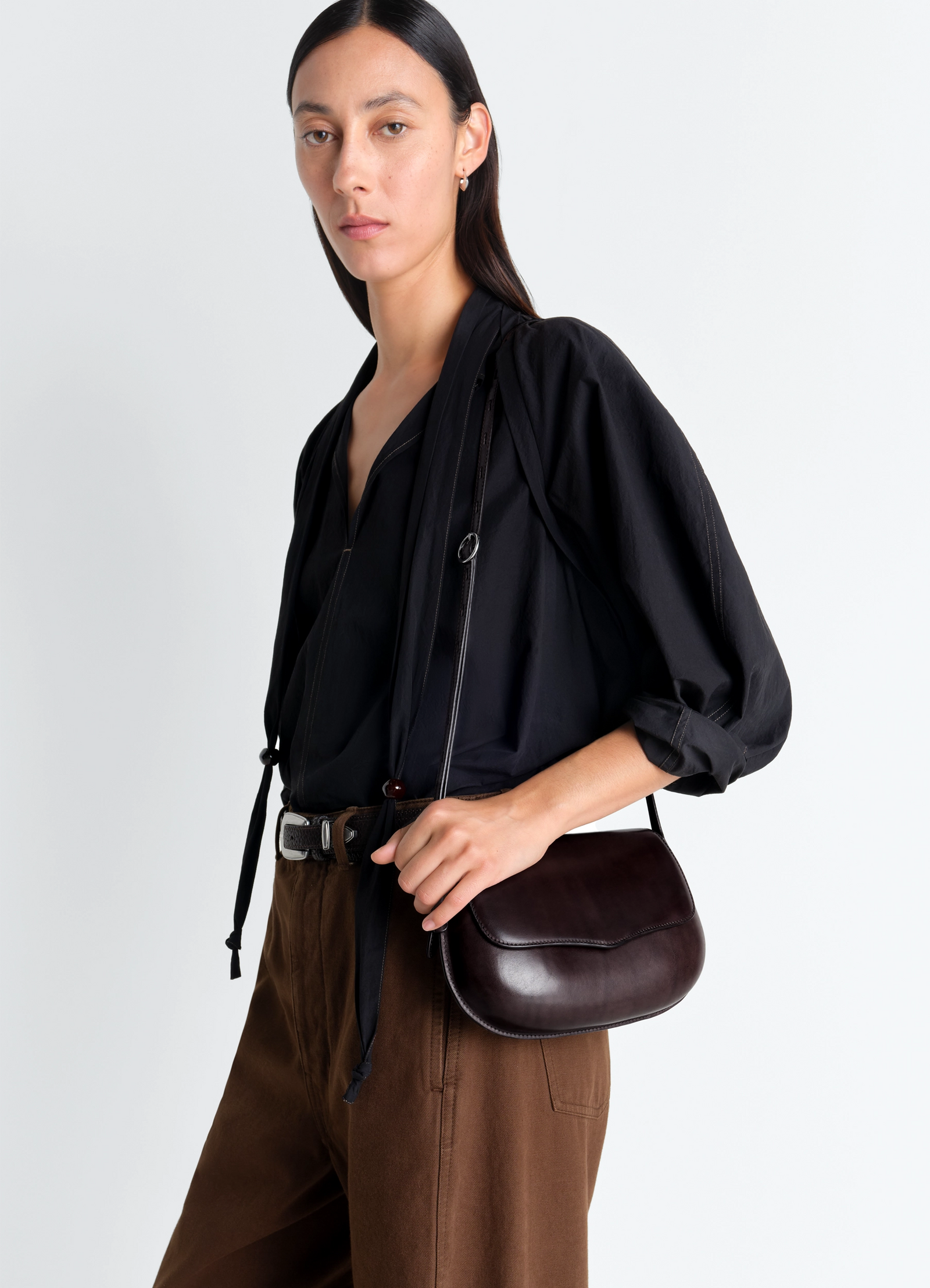 Lemaire belly bag in patinated silver leather, model shot, side view smooth curved silhouette