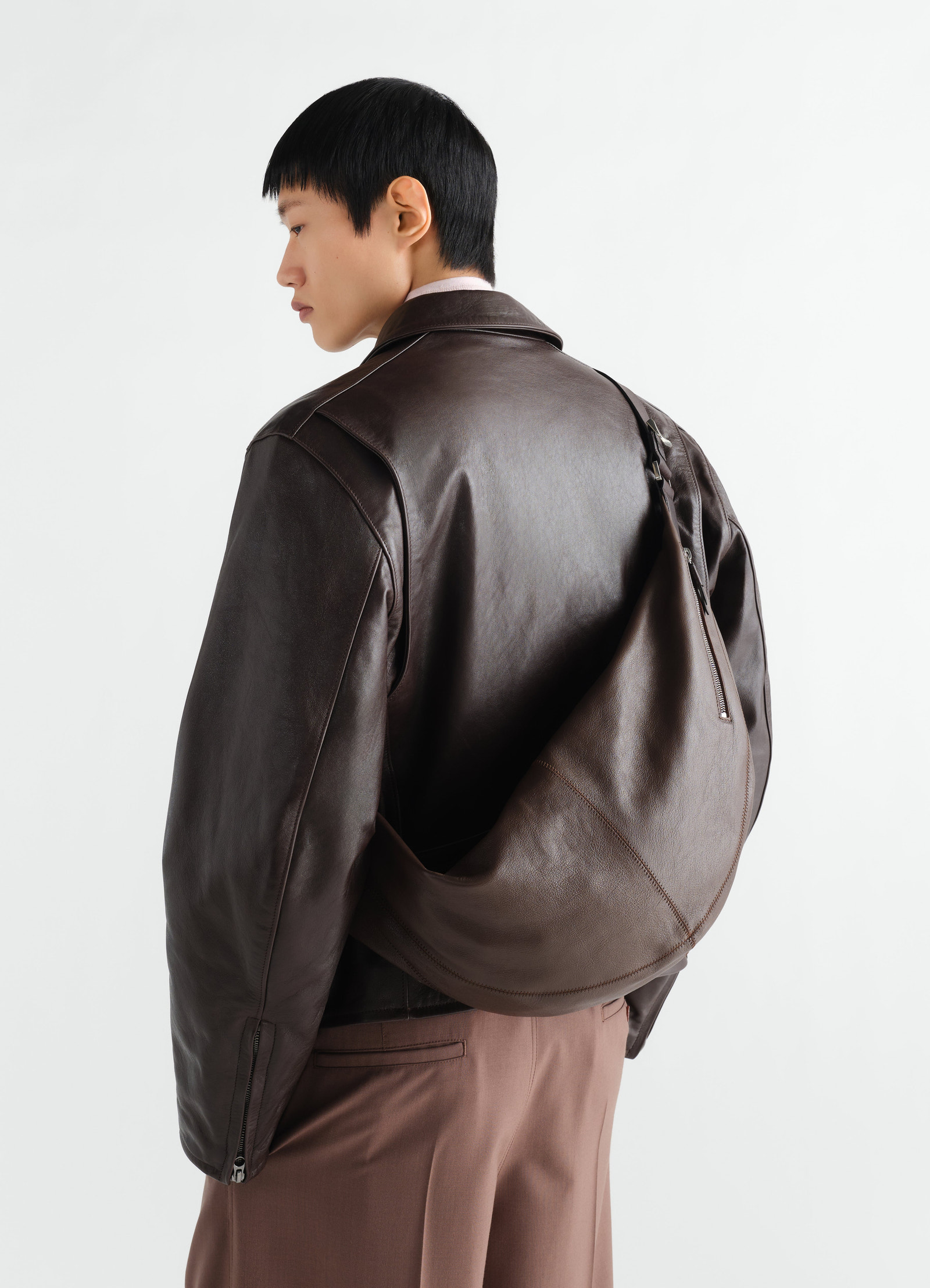 Quiver clip bag in dark brown leather lemaire worn by a model back view with zip detail and stitched design